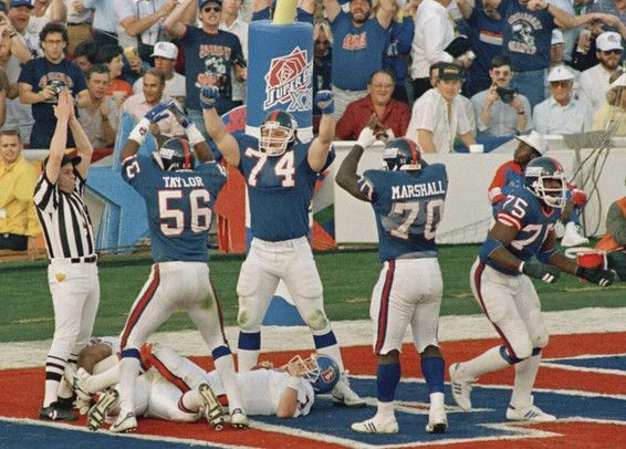 New York Giants defenders Lawrence Taylor (#56), Erik Howard (#74) and Leonard Marshall celebrate over Denver Broncos quarterback John Elway after he was sacked by defensive end George Martin (#75) for a safety in the second quarter of Super Bowl XXI.